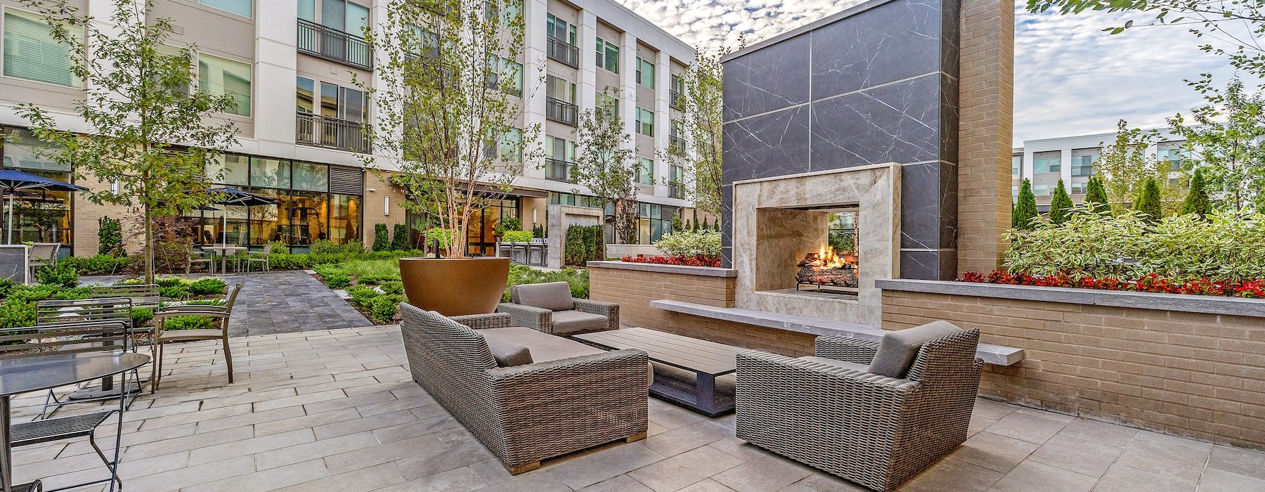 The outdoor lounge at Sagewell Hanover Apartments For Rent in Hanover, MA, featuring a fireplace and outdoor furniture.