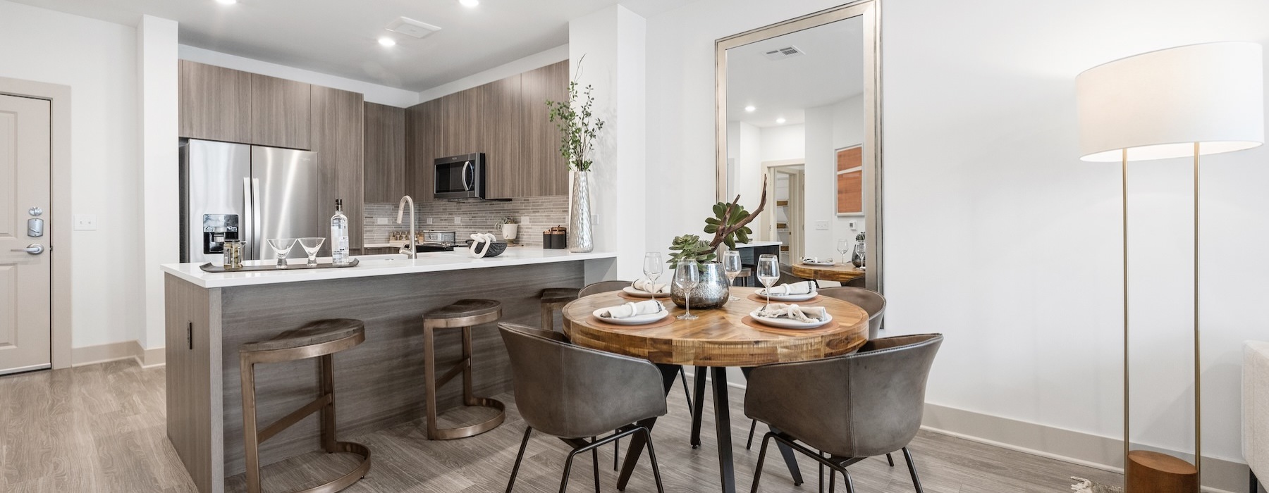 Model kitchen and dining room at Sagewell Hanover Apartments For Rent in Hanover, MA, featuring wood grain floor paneling.