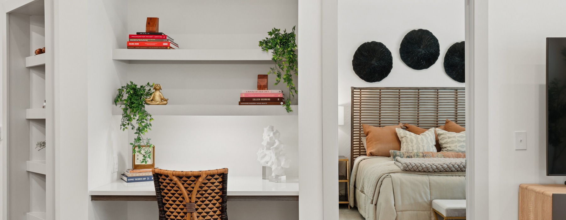 A built in work from home desk with shelves and view of bedroom in distance.